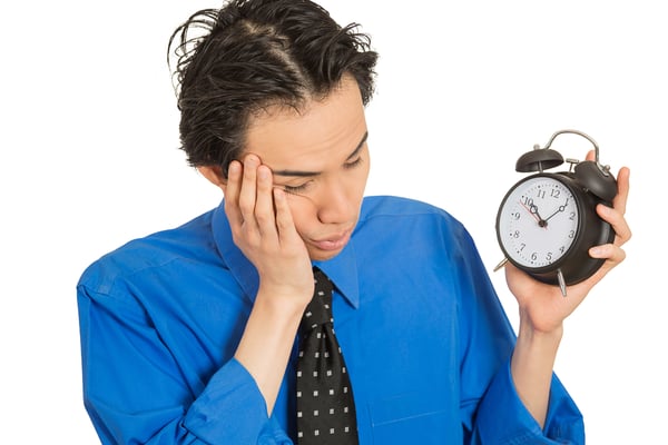 Portrait sleeping young man holding alarm clock isolated on white background. Long working hours, lack of sleep, sleep deprivation, no motivation concept. Face expression